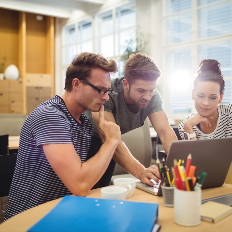 Group of graphic designers discussing over laptop at their desk