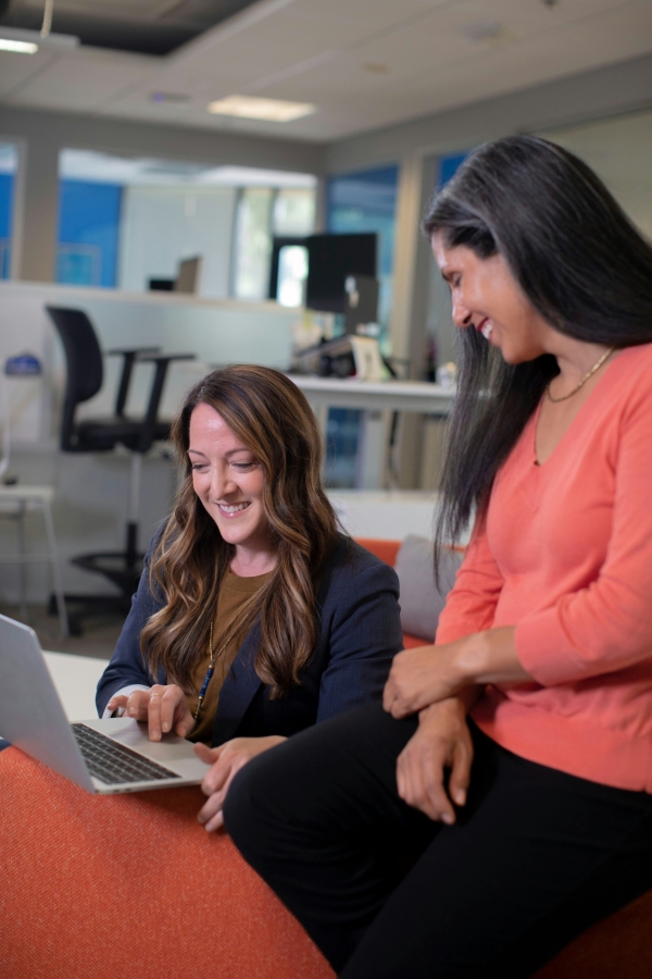 Two women working and laughing on laptop