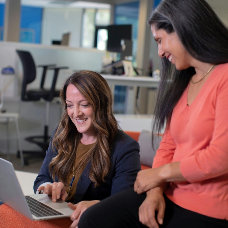 Two women working and laughing on laptop