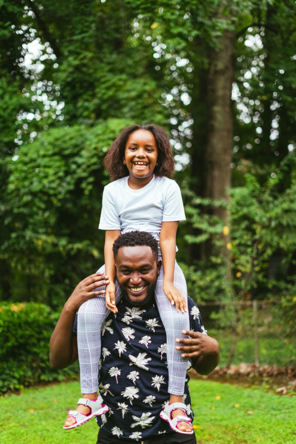 a man and two women holding a child on their shoulders